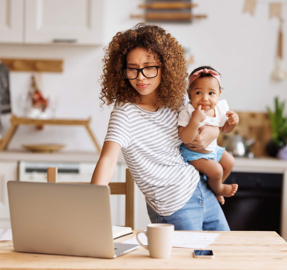 mom with baby on hip working on laptop